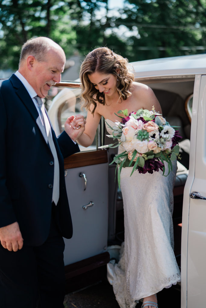 Father helping bride out of the limo